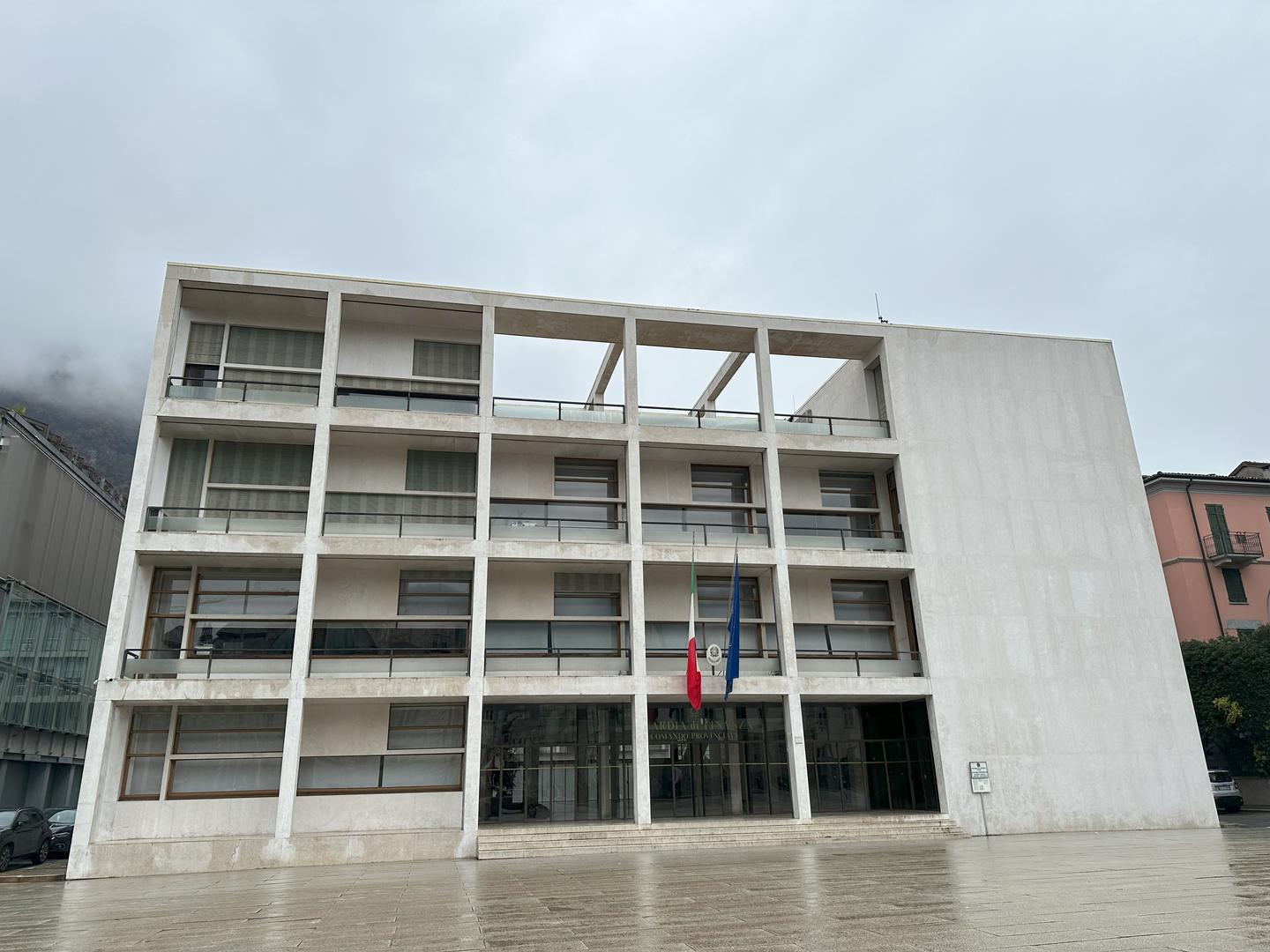 Brutalist white concrete office building under overcast skies.