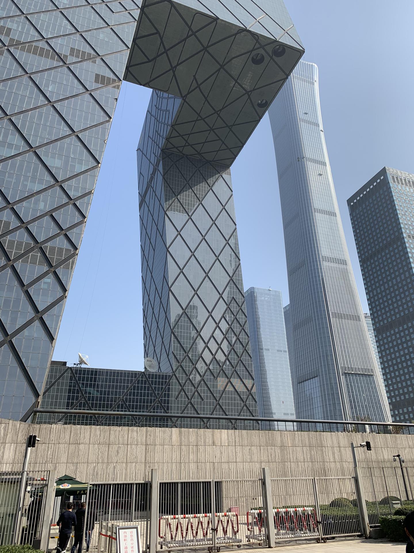 Ground-level view of geometric skyscraper and partial view of Beijing skyline.