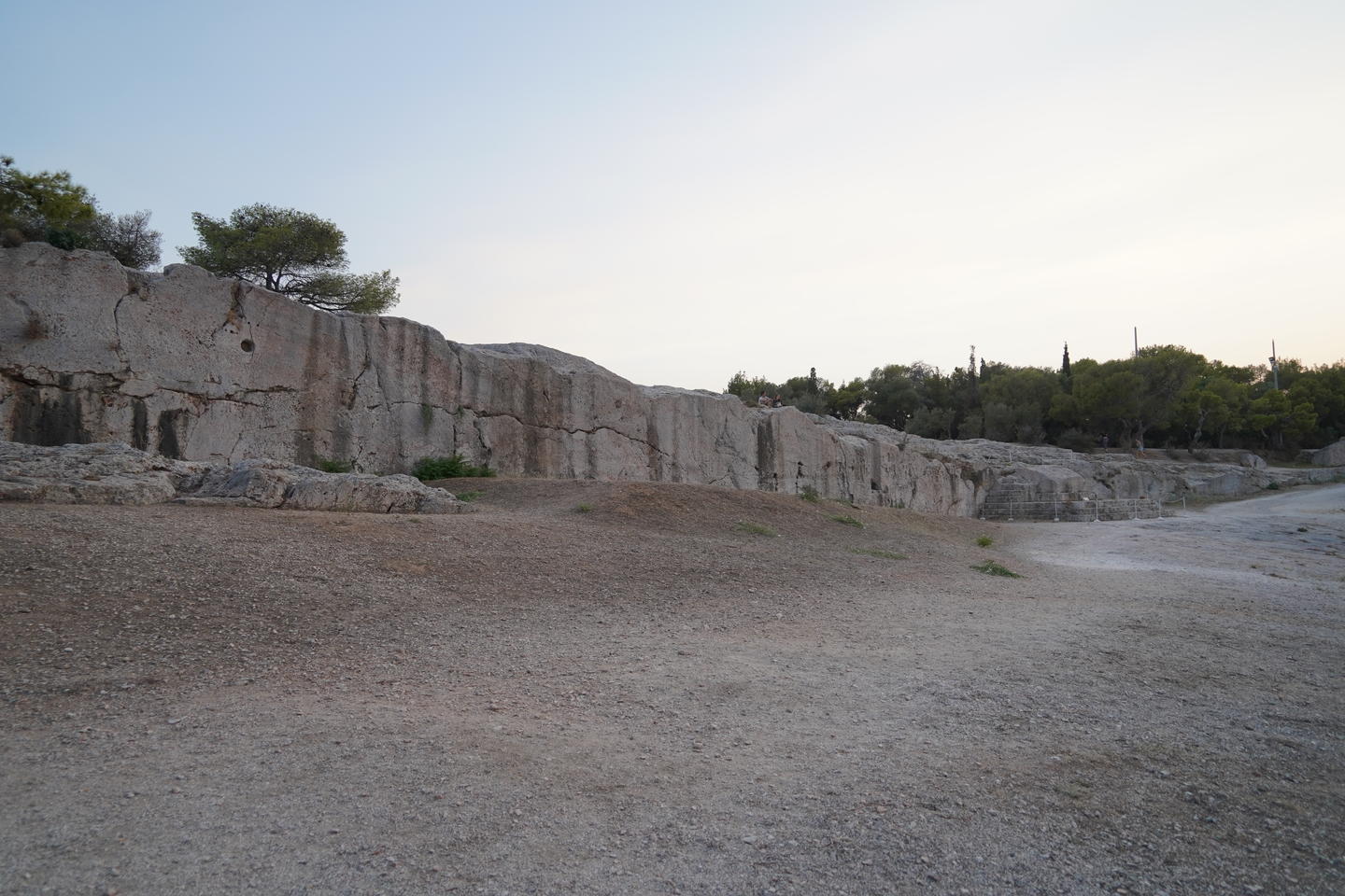 Evening view of the ancient stone wall of Pnyx surrounded by stone and trees which is considered the Birthplace of Democracy.