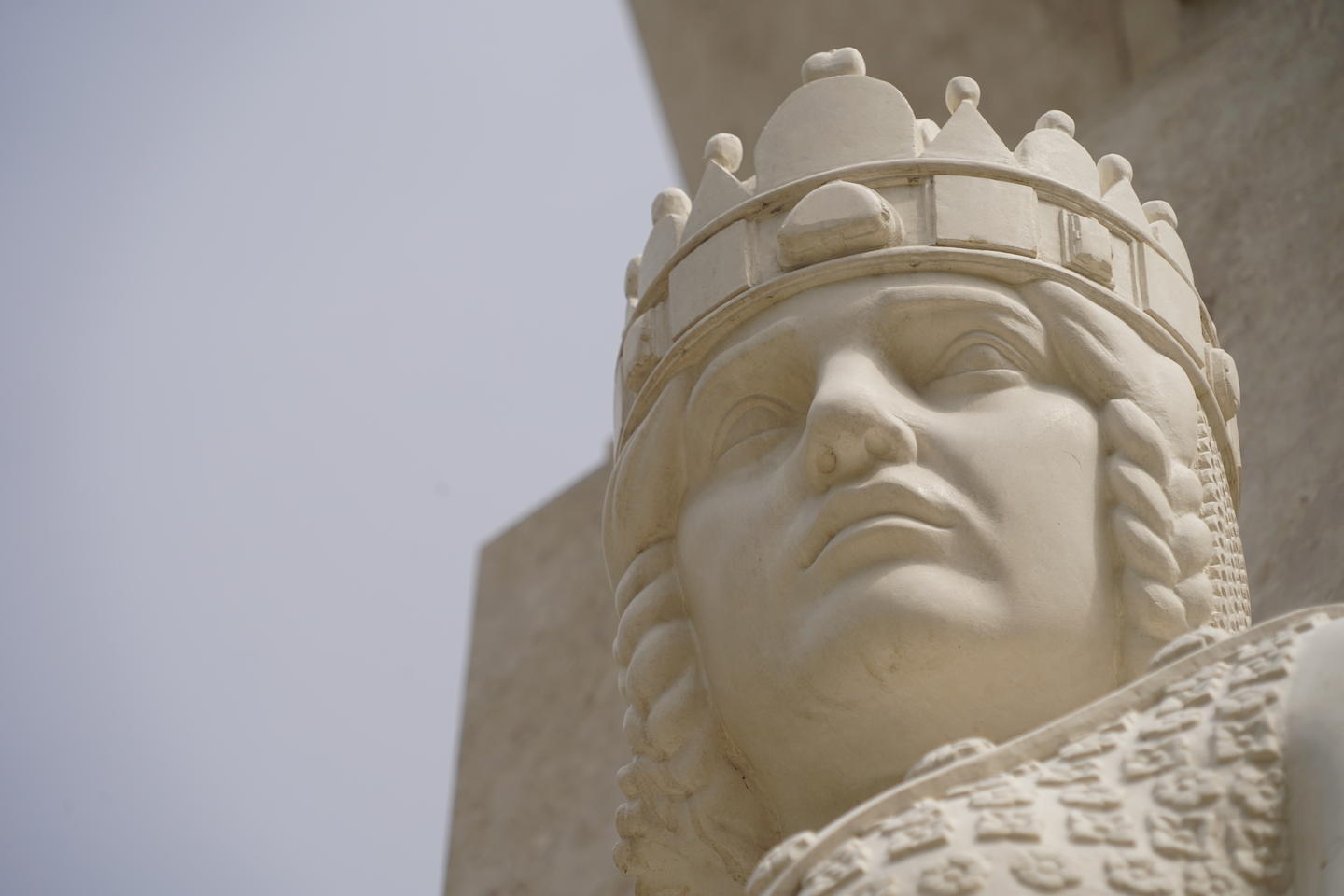 Close up detail of the stern face, braided hair, and crown on the statue at the reconstructed Monument of National Martyrs in Budapest